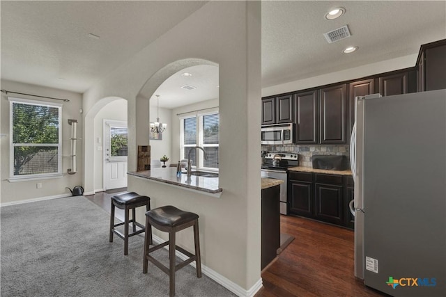 6333 Iris Run, New Braunfels, TX 78132 - kitchen featuring stainless steel appliances, arched walkways, a breakfast bar area, tasteful backsplash, and a chandelier