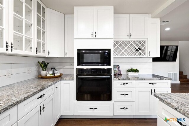 kitchen featuring built in microwave, visible vents, black oven, and white cabinets