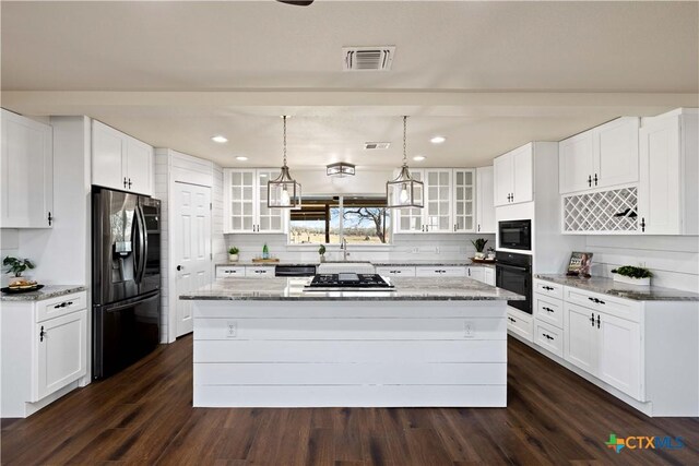 kitchen with dark wood finished floors, a kitchen island, black appliances, and glass insert cabinets