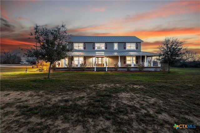 view of front of property featuring metal roof, a porch, and a front lawn