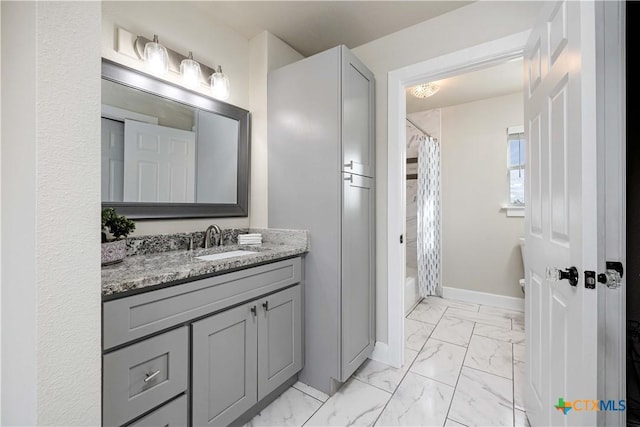 full bath with marble finish floor, vanity, baseboards, and shower / bathtub combination with curtain