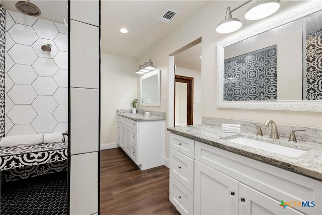 full bath featuring visible vents, two vanities, a sink, wood finished floors, and recessed lighting