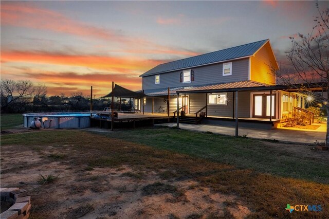 rear view of property featuring an outdoor pool, a yard, and metal roof