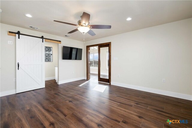 empty room featuring visible vents, baseboards, a barn door, recessed lighting, and dark wood-style flooring