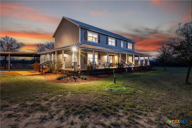 farmhouse inspired home with covered porch, metal roof, and a front lawn