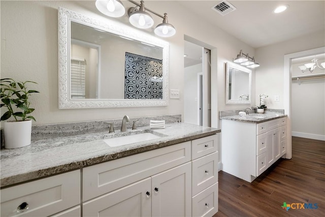 full bathroom featuring visible vents, wood finished floors, two vanities, and a sink