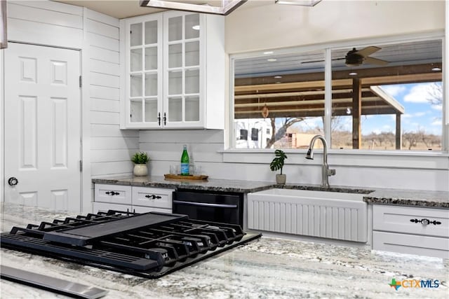 kitchen with a sink, white cabinetry, a wealth of natural light, and black gas stovetop