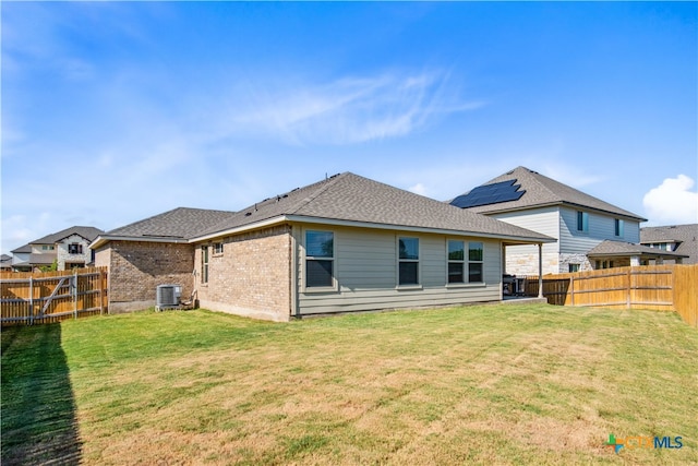 back of property with central AC unit and a lawn