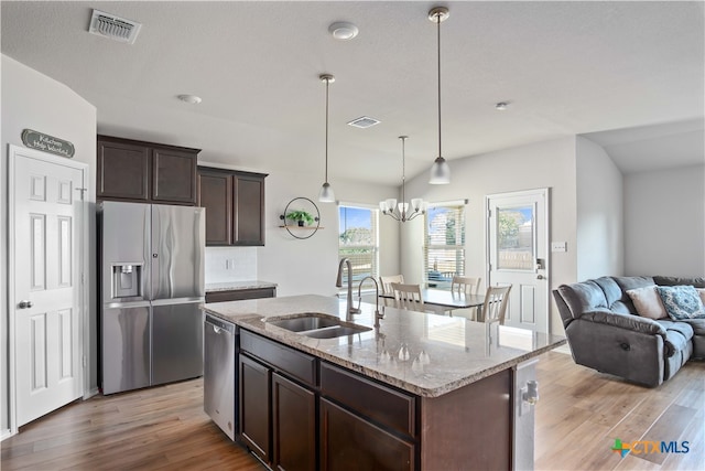 kitchen with light wood-type flooring, appliances with stainless steel finishes, sink, and an island with sink