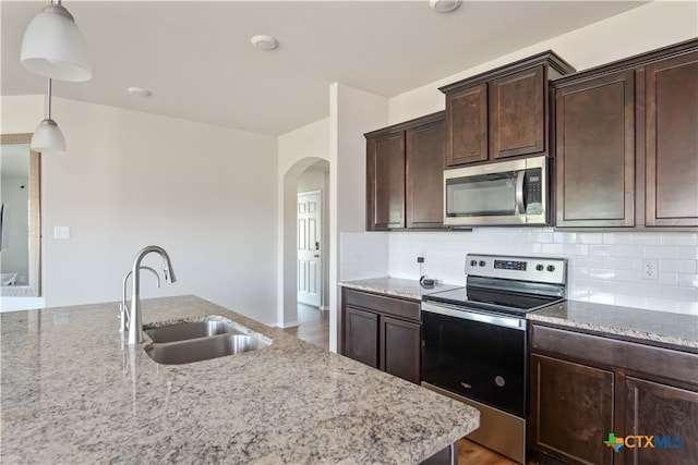 kitchen featuring light stone counters, hardwood / wood-style floors, hanging light fixtures, sink, and appliances with stainless steel finishes