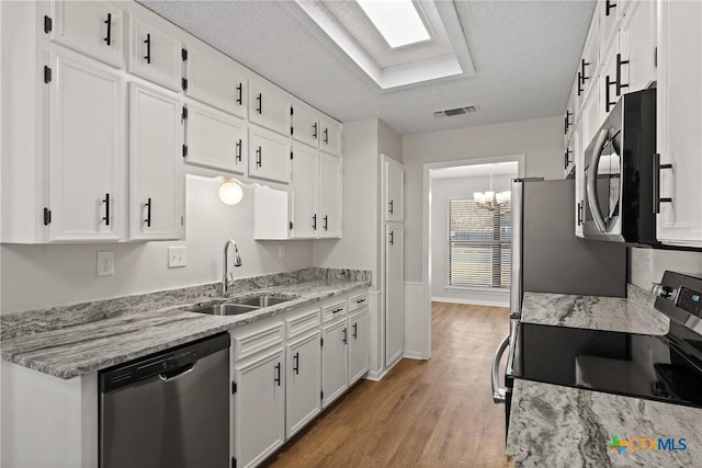 kitchen with sink, stainless steel appliances, light stone countertops, white cabinets, and light wood-type flooring