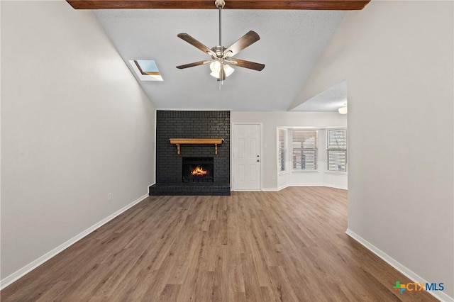 unfurnished living room with vaulted ceiling, a brick fireplace, light hardwood / wood-style flooring, a textured ceiling, and ceiling fan