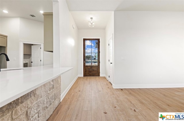 entryway featuring lofted ceiling, light hardwood / wood-style floors, a notable chandelier, and sink