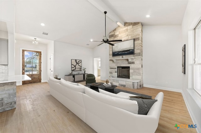 living room with lofted ceiling with beams, ceiling fan, light wood-type flooring, and a fireplace