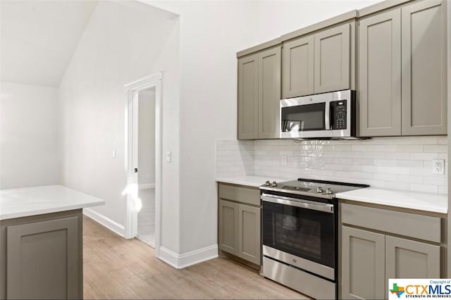 122 Overlook Trl, Copperas Cove, TX 76522 - kitchen with stainless steel appliances, gray cabinetry, light wood-style flooring, decorative backsplash, and vaulted ceiling