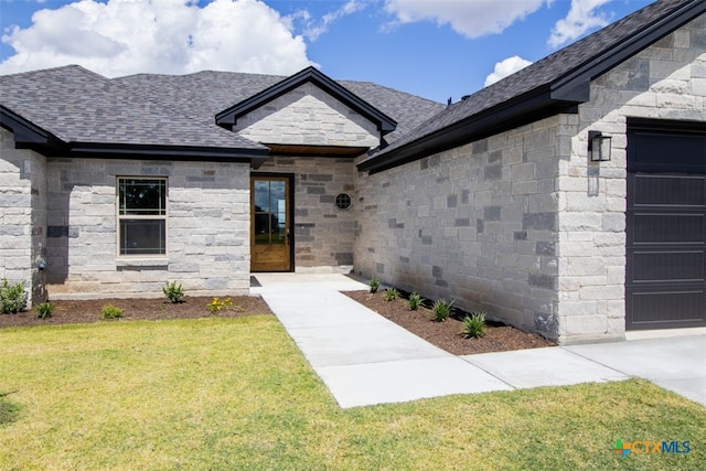 entrance to property featuring a lawn and a garage