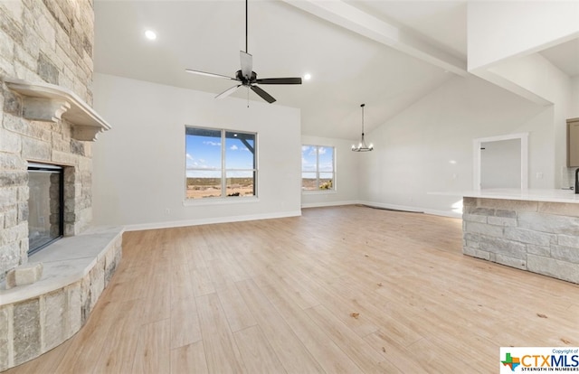 unfurnished living room featuring beam ceiling, light hardwood / wood-style flooring, high vaulted ceiling, a fireplace, and ceiling fan with notable chandelier