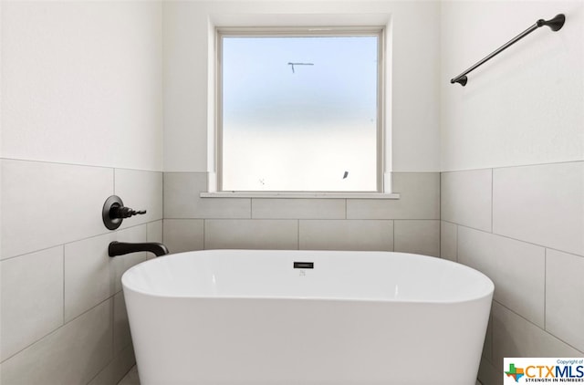 bathroom with a bathtub and tile walls