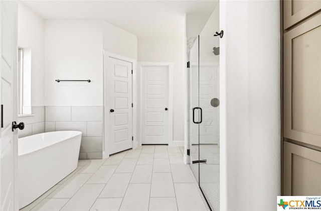 bathroom with tile patterned flooring, shower with separate bathtub, and tile walls