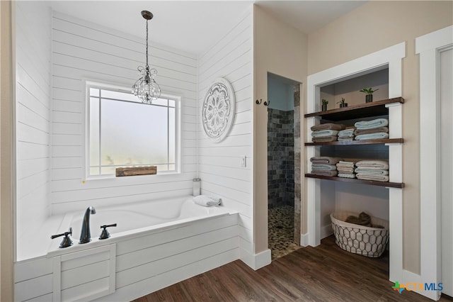 bathroom with hardwood / wood-style flooring, an inviting chandelier, and separate shower and tub