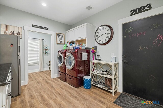 washroom with separate washer and dryer, light hardwood / wood-style flooring, and cabinets