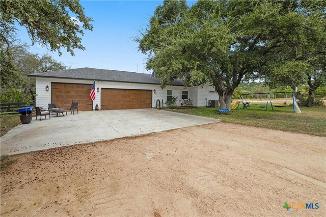 view of front of house featuring a playground, a garage, and a front lawn