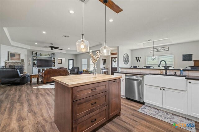 kitchen with a fireplace, hanging light fixtures, dark wood-type flooring, stainless steel dishwasher, and ceiling fan