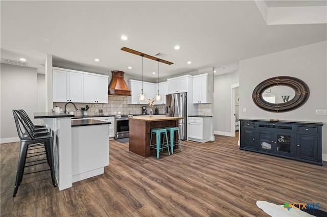 kitchen featuring dark wood-type flooring, white cabinetry, premium range hood, and stainless steel appliances