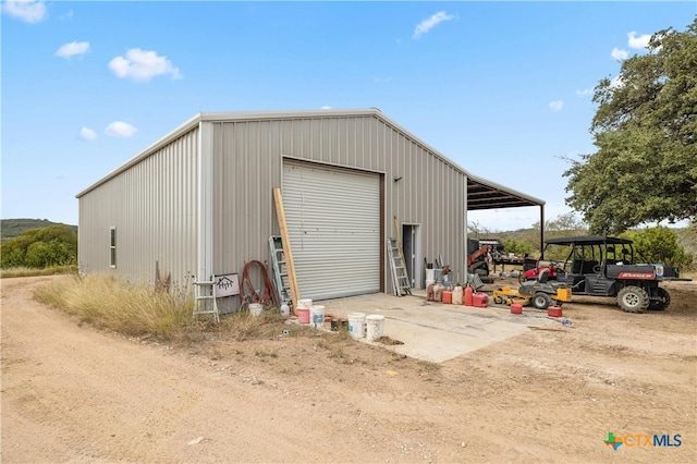 view of outdoor structure with a garage and a carport