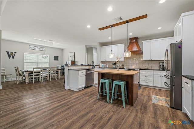 kitchen featuring dark hardwood / wood-style floors, custom exhaust hood, a kitchen island with sink, white cabinets, and pendant lighting