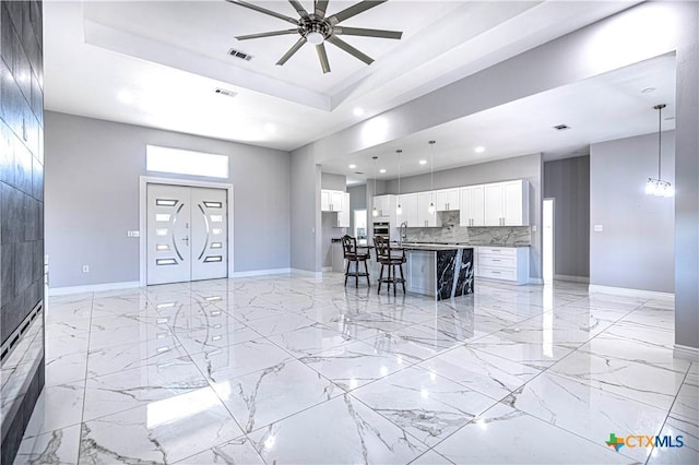 kitchen featuring hanging light fixtures, a kitchen island, decorative backsplash, a breakfast bar, and white cabinets