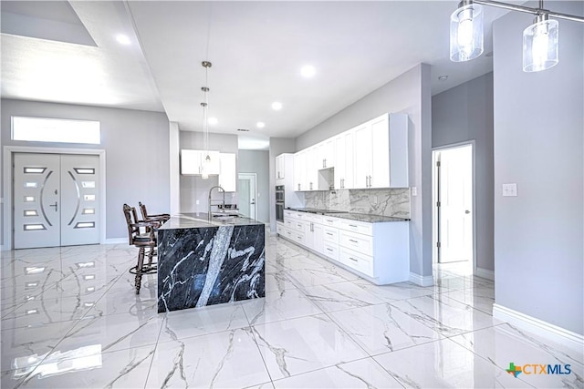 kitchen with decorative backsplash, sink, pendant lighting, dark stone countertops, and white cabinets