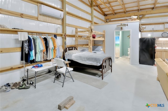 bedroom with a wall unit AC, ensuite bathroom, black fridge, and sink