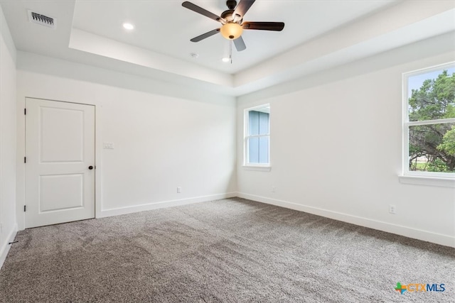 spare room with carpet flooring, ceiling fan, and a tray ceiling