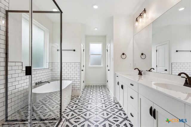 5116 Goliad Dr, Temple, TX 76502 - full bathroom featuring healthy amount of natural light, double vanity, a soaking tub, a stall shower, and recessed lighting