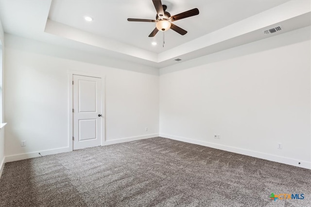 spare room featuring ceiling fan, a raised ceiling, and carpet floors