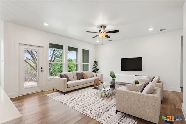 living room with light hardwood / wood-style flooring and ceiling fan