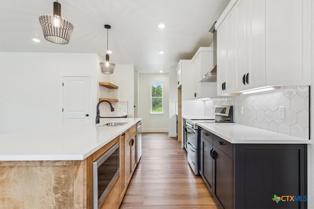 kitchen featuring light hardwood / wood-style floors, sink, appliances with stainless steel finishes, hanging light fixtures, and white cabinets