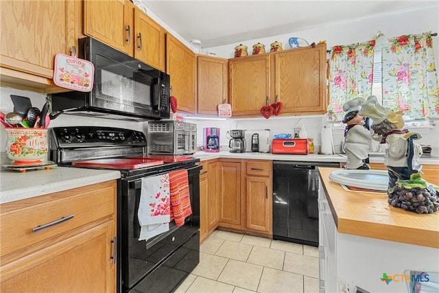 kitchen with light tile patterned flooring, sink, and black appliances