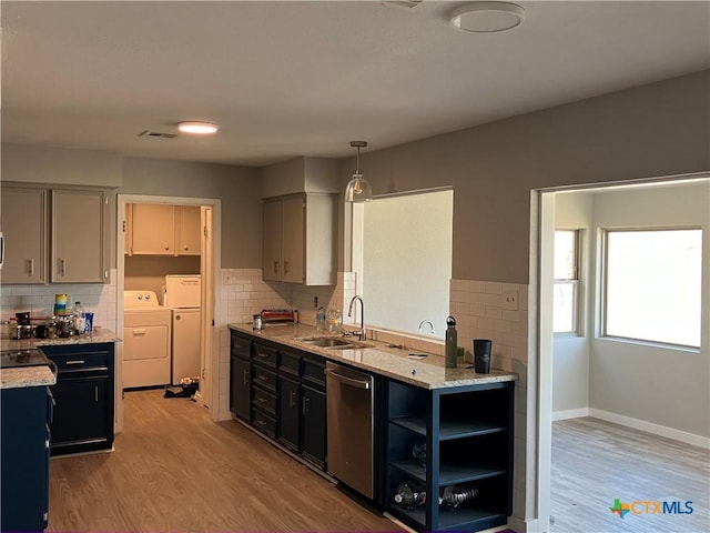 kitchen with sink, washing machine and dryer, light hardwood / wood-style floors, decorative light fixtures, and stainless steel dishwasher