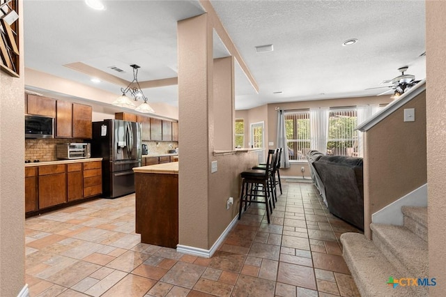 2123 Grizzly Trl, Harker Heights, TX 76548 - kitchen featuring stainless steel appliances, open floor plan, brown cabinets, decorative backsplash, and a kitchen bar