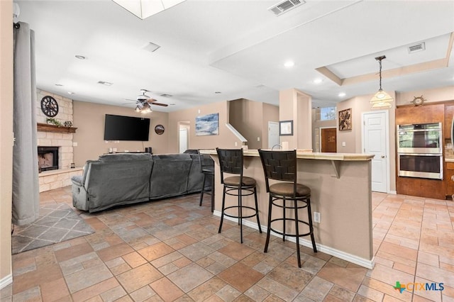 2123 Grizzly Trl, Harker Heights, TX 76548 - kitchen with stainless steel double oven, stone tile flooring, a breakfast bar area, a fireplace, and recessed lighting