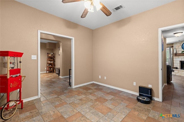 2123 Grizzly Trl, Harker Heights, TX 76548 - unfurnished room featuring stone tile flooring, ceiling fan, arched walkways, and a stone fireplace