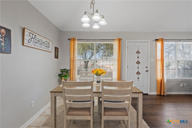 dining space with dark hardwood / wood-style floors, plenty of natural light, and an inviting chandelier