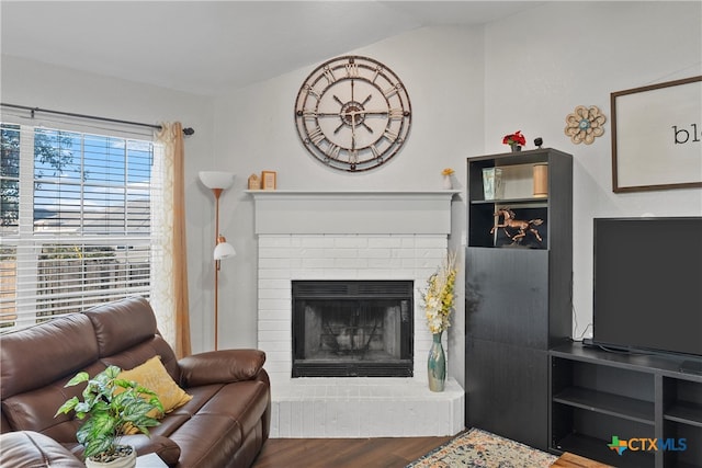 living room featuring a brick fireplace, wood-type flooring, and lofted ceiling