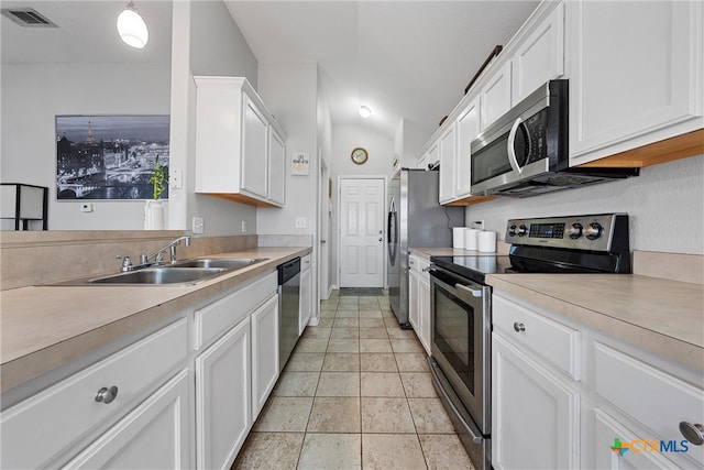 kitchen featuring sink, appliances with stainless steel finishes, decorative light fixtures, white cabinets, and vaulted ceiling