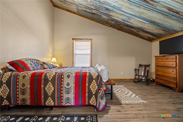 bedroom featuring lofted ceiling, baseboards, and wood finished floors