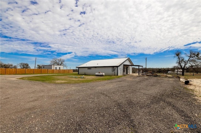 view of side of property featuring an outbuilding, a pole building, fence, and driveway