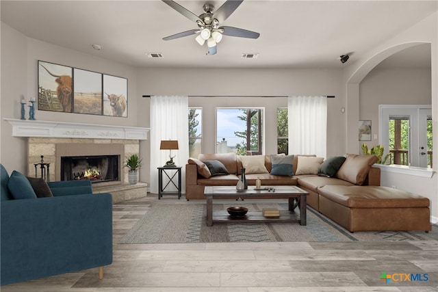 living room featuring a fireplace, ceiling fan, and light hardwood / wood-style flooring