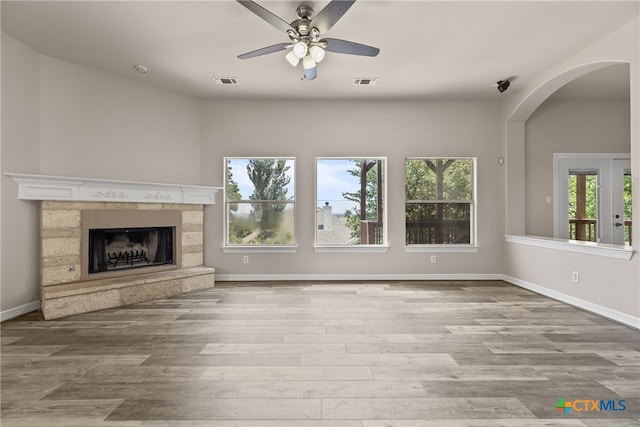 unfurnished living room with a fireplace, a wealth of natural light, ceiling fan, and light hardwood / wood-style flooring